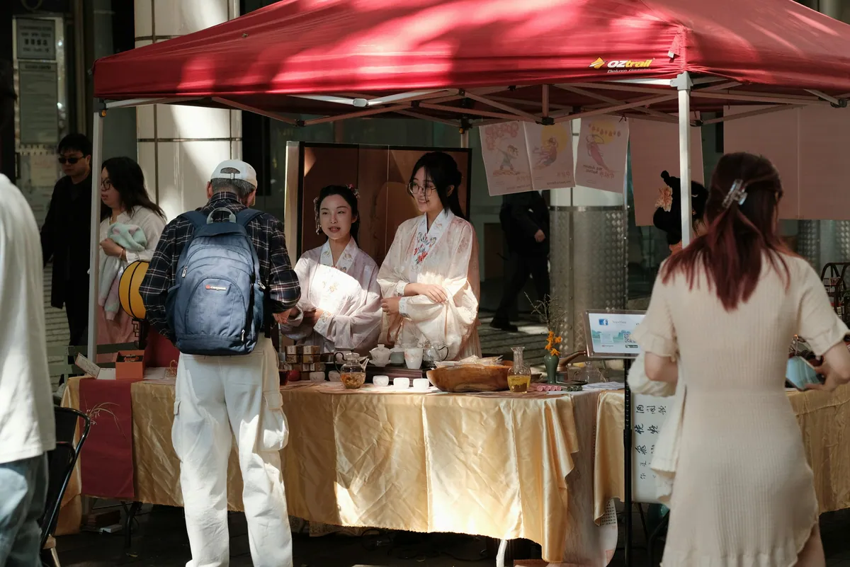 A busy market stall under a red umbrella